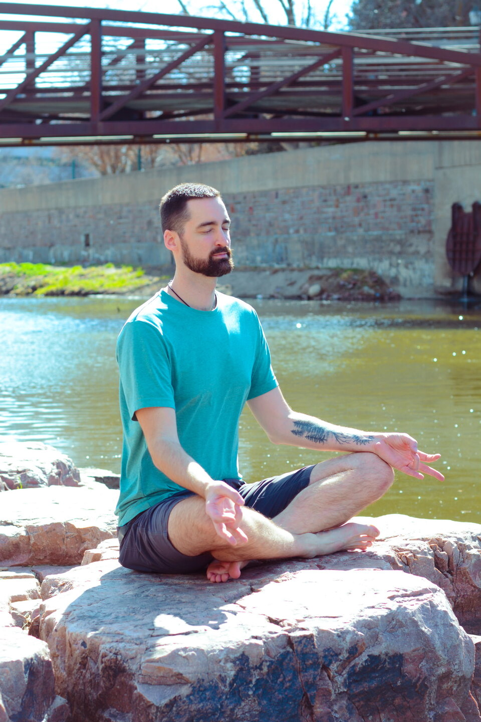 Brandon Pogge seated in meditation beside the water.